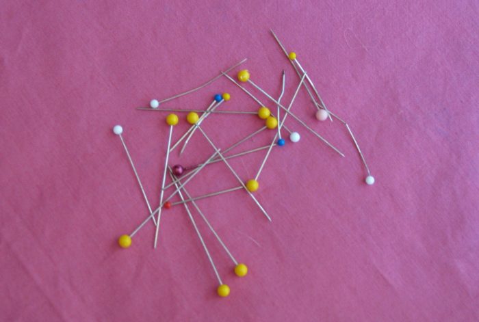 Булавки на розовой ткани