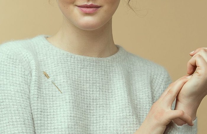 Девушка в свитере, которому приколота декоративная булавка